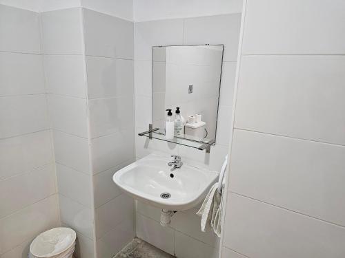 Baño blanco con lavabo y espejo en MHrosa, en Valencia