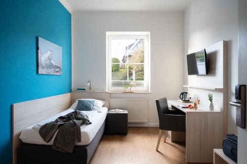 a bedroom with a bed and a desk and a window at Hotel Alte Fischereischule in Eckernförde