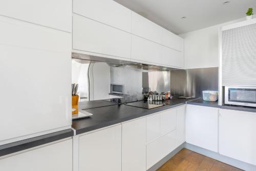 une cuisine blanche avec des armoires blanches et un micro-ondes dans l'établissement Appartement Rodina - Welkeys, à Issy-les-Moulineaux