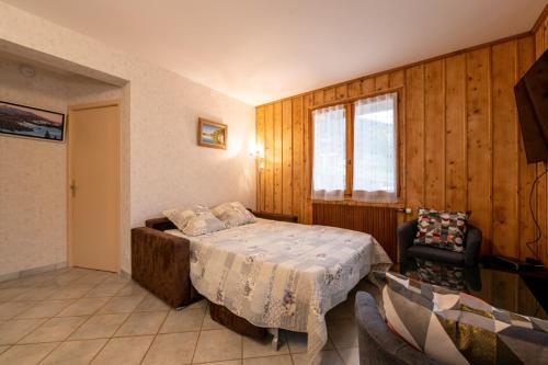 ein Schlafzimmer mit einem Bett, einem Fenster und einem Stuhl in der Unterkunft Chalet Le Valserine les Bouvettes in Lélex