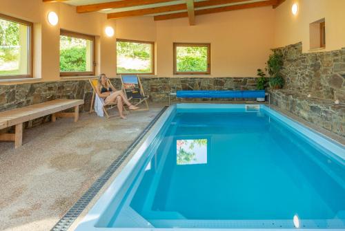 a woman sitting in a chair next to a swimming pool at Podveský mlýn in Tlumačov