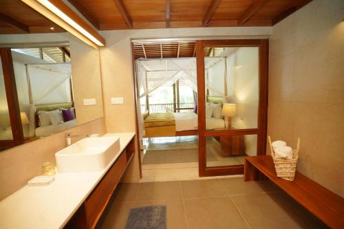 a bathroom with a sink and a mirror and a bedroom at Maison Samara in Hikkaduwa