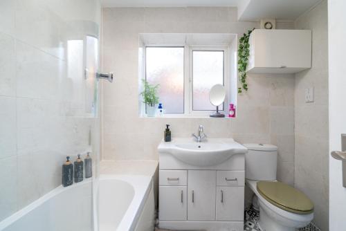 a bathroom with a sink toilet and a window at Madika Homes - Cosy Edgware 2 Bed Flat with Free parking in Edgware