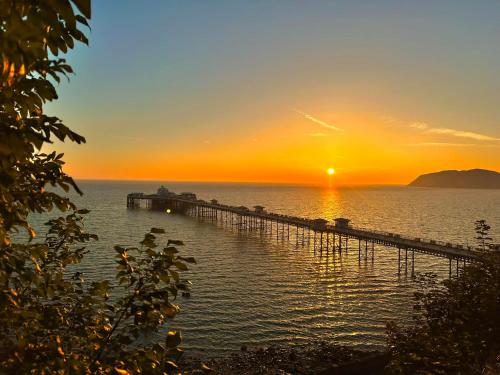 a pier in the water with the sunset in the background at Pebble House in Llandudno