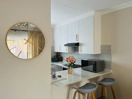 una cocina con un reloj en la pared y dos taburetes en Wanderlust 2-bedroom Apartment, en Centurion