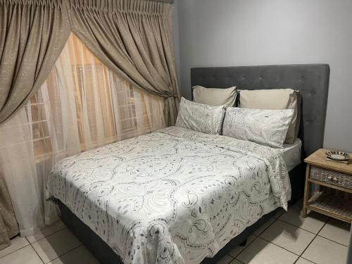a bedroom with a bed with a white comforter and a window at When in the Middle Self Catering Guest House in Durban