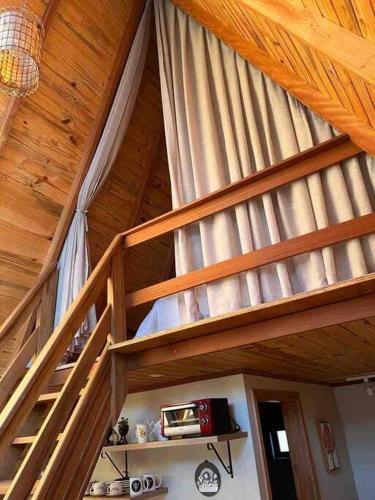 a loft bed in a room with a wooden ceiling at Chalé de madeira com vista para o rio in Pomerode