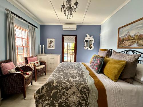 ein Schlafzimmer mit blauen Wänden sowie einem Bett und Stühlen in der Unterkunft A State of Grace in Clanwilliam