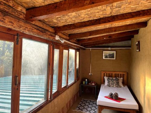 1 dormitorio con cama y ventana grande en Glampinn Woods, en Nainital