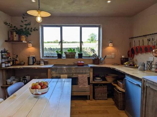 una cocina con una mesa con un tazón de manzanas. en Stylish 3 bed Cotswold cottage with stunning views, en Cheltenham