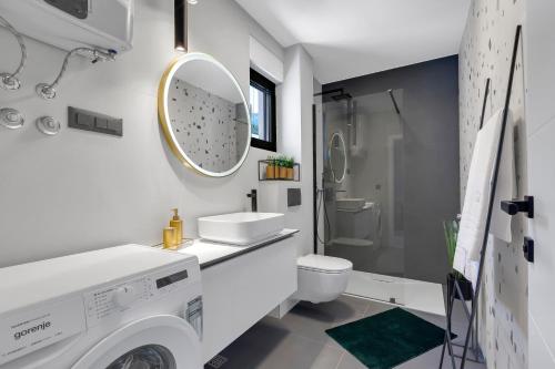 a white bathroom with a washer and dryer in it at Villa Bomada in Tučepi