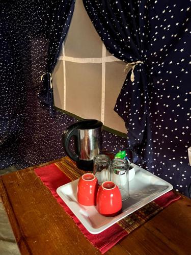 a table with a plate with two cups and a coffee pot at Glampinn Woods in Nainital
