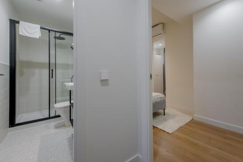 a bathroom with a shower and a toilet and a bed at Modern Apt & Cool interior design a 20 metros del Retiro in Madrid