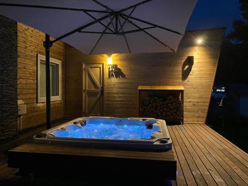 a hot tub on a deck with an umbrella at The Lake House 野尻湖 in Shinano