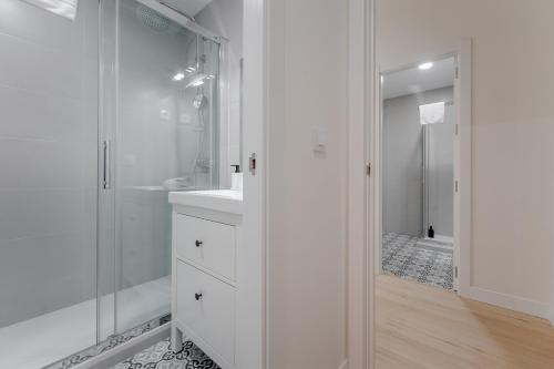 baño blanco con ducha y lavamanos en Modern Apt para 6pax en la Plaza de Tirso-Centro, en Madrid