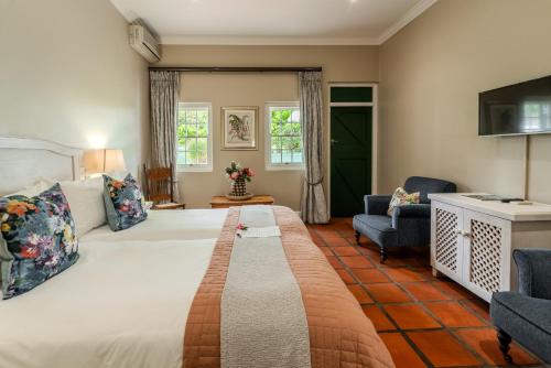 a bedroom with a large bed and a living room at Eikendal Lodge in Stellenbosch