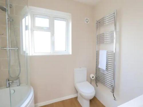 biała łazienka z toaletą i oknem w obiekcie Pass the Keys Spacious 3BR Garden Home inc Parking Oxford w Oksfordzie