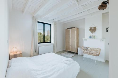 a white bedroom with a bed and a window at Maison Héromie - vakantiewoning Damme - 8 personen in Damme