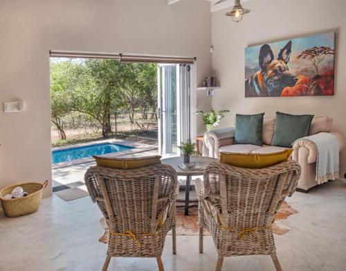 a living room with a table and chairs and a pool at Wild Honey Studio in Marloth Park