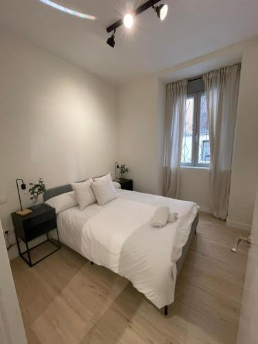 Un dormitorio blanco con una cama grande y una ventana en Bajo Duplex 7pax a 5 min de Gran Via-Malasana, en Madrid