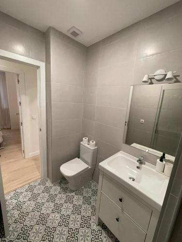 uma casa de banho com um WC, um lavatório e um espelho. em Bajo Duplex 7pax a 5 min de Gran Via-Malasana em Madri