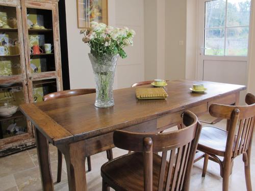une table de salle à manger avec un vase de fleurs dessus dans l'établissement Le Coteau du Seigneur, à Laize-la-Ville