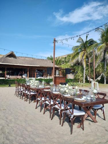 a long row of tables and chairs on the beach at Oceanfront Casa Rhino in Paso Hondo