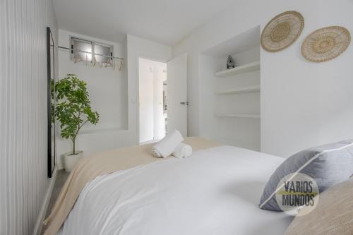 a white bedroom with a large bed and a potted plant at Atico Calle Silva para 3pax con terraza esquina con Gran Via in Madrid