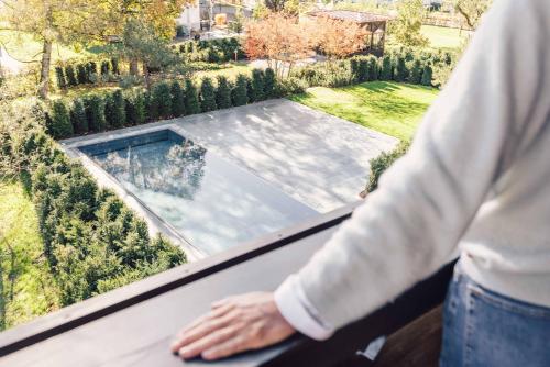 a person standing on a balcony looking at a swimming pool at Posthotel Taube in Schruns-Tschagguns