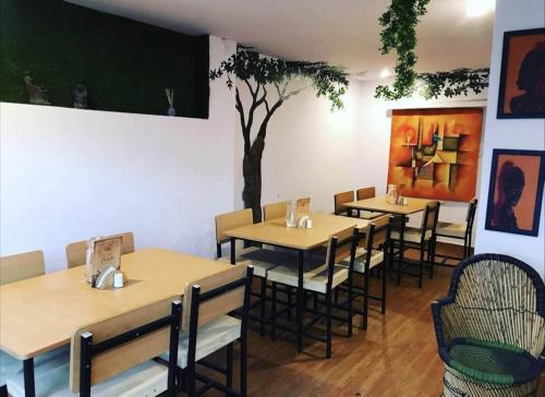 a restaurant with tables and chairs and a tree on the wall at Hostel Nirvana in Udaipur