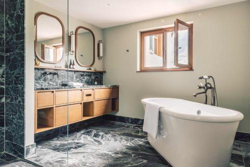 a bathroom with a tub and a sink at Posthotel Taube in Schruns-Tschagguns