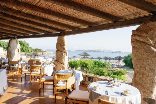 ein Restaurant mit Tischen und Stühlen und Meerblick in der Unterkunft Hotel Pitrizza, Costa Smeralda in Porto Cervo