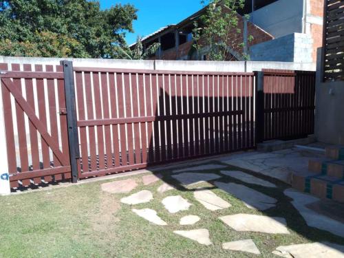 a wooden fence with a gate in a yard at Ramos Acomodações in Búzios