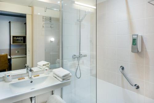 y baño con ducha y lavamanos. en Hôtel La Solitude, en Lourdes