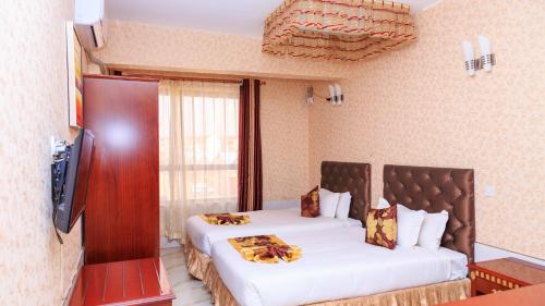 a bedroom with two beds and a flat screen tv at Easy Hotel Kenya in Nairobi