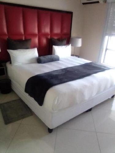 a large bed with a red headboard in a bedroom at Dineo's Lodge and Spa in Burgersfort