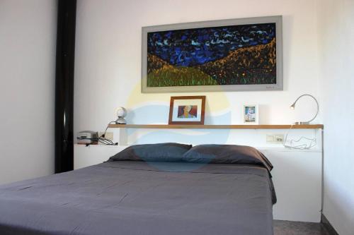 a bedroom with a bed and a painting on the wall at Llevantada - Casa en Poblenou del Delta con piscina privada y barbacoa in El Poblenou del Delta