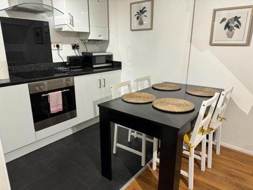 uma cozinha com uma mesa preta e armários brancos em Summer House Sleeps 6 , 2 Large Parking Spaces, walking distance to Cardiff Bay and City Centre em Cardiff