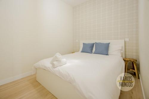 Centrico and Cozy Apt para 9pax en Calle San Dimas في مدريد: غرفة نوم بسرير ابيض مع مخدات زرقاء