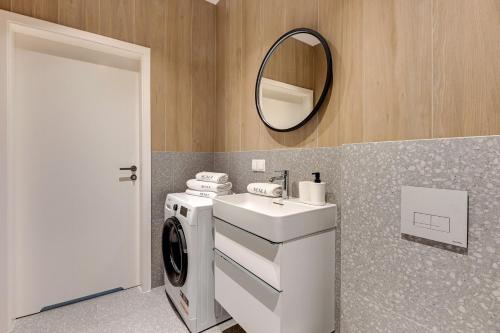 a bathroom with a sink and a washing machine at Scala Apartamenty by Moderna Profit- Łąkowa 60C in Gdańsk