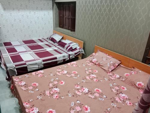 um quarto com duas camas com flores cor-de-rosa em KIRTI SEVA SADAN em Mathura