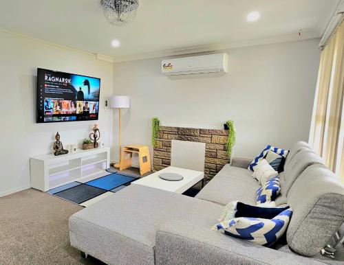 uma sala de estar com um sofá e uma televisão em Miami Stay em Auckland