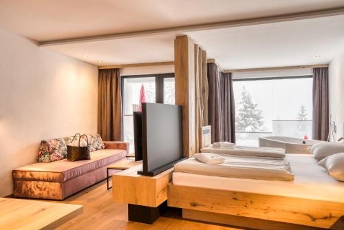 a hotel room with two beds and a tub at Ursprung Panorama Hotel Königsleiten in Königsleiten