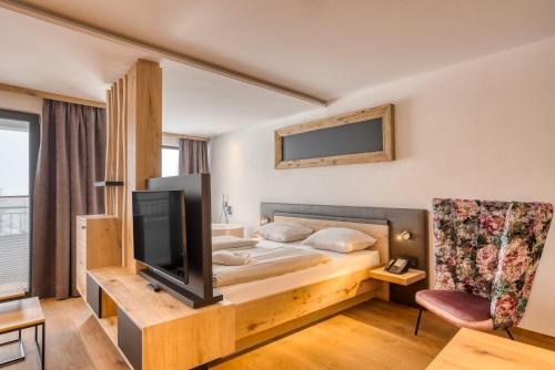 a hotel room with a bed and a tv at Ursprung Panorama Hotel Königsleiten in Königsleiten