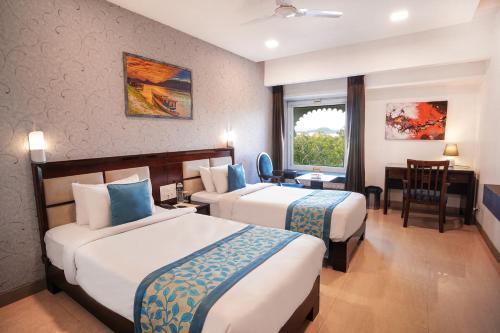 Horizon Hotel في أودايبور: غرفة فندقية بسريرين وطاولة وكراسي