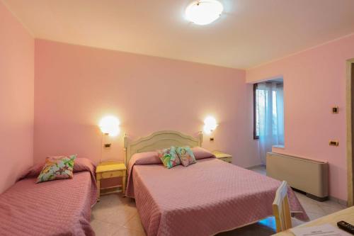 two beds in a room with pink walls at Hotel Solanas in Solanas