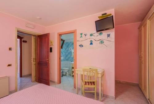 um quarto com uma mesa e uma televisão na parede em Hotel Solanas em Solanas