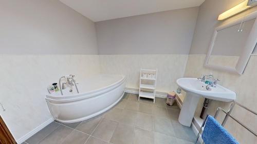 a bathroom with a white tub and a sink at The Barn. in Carmarthen