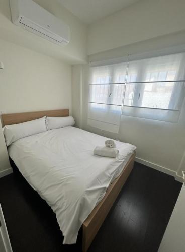 Un dormitorio con una cama blanca con una toalla. en Magnifico Apt 1hab 3 pax en plena plaza de Chueca, en Madrid