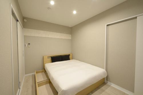 um pequeno quarto com uma cama branca em 最大１０名宿泊可能　２世帯や友人家族と過ごす沖縄 em Enobi